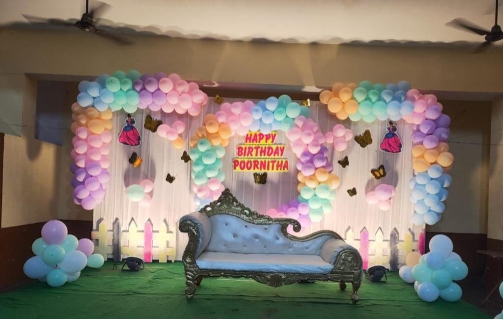 Pastel balloon birthday backdrop with vintage lounge seat