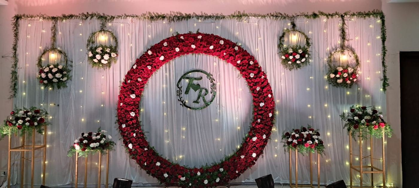 Wedding photo backdrop with large red rose ring and couple monogram